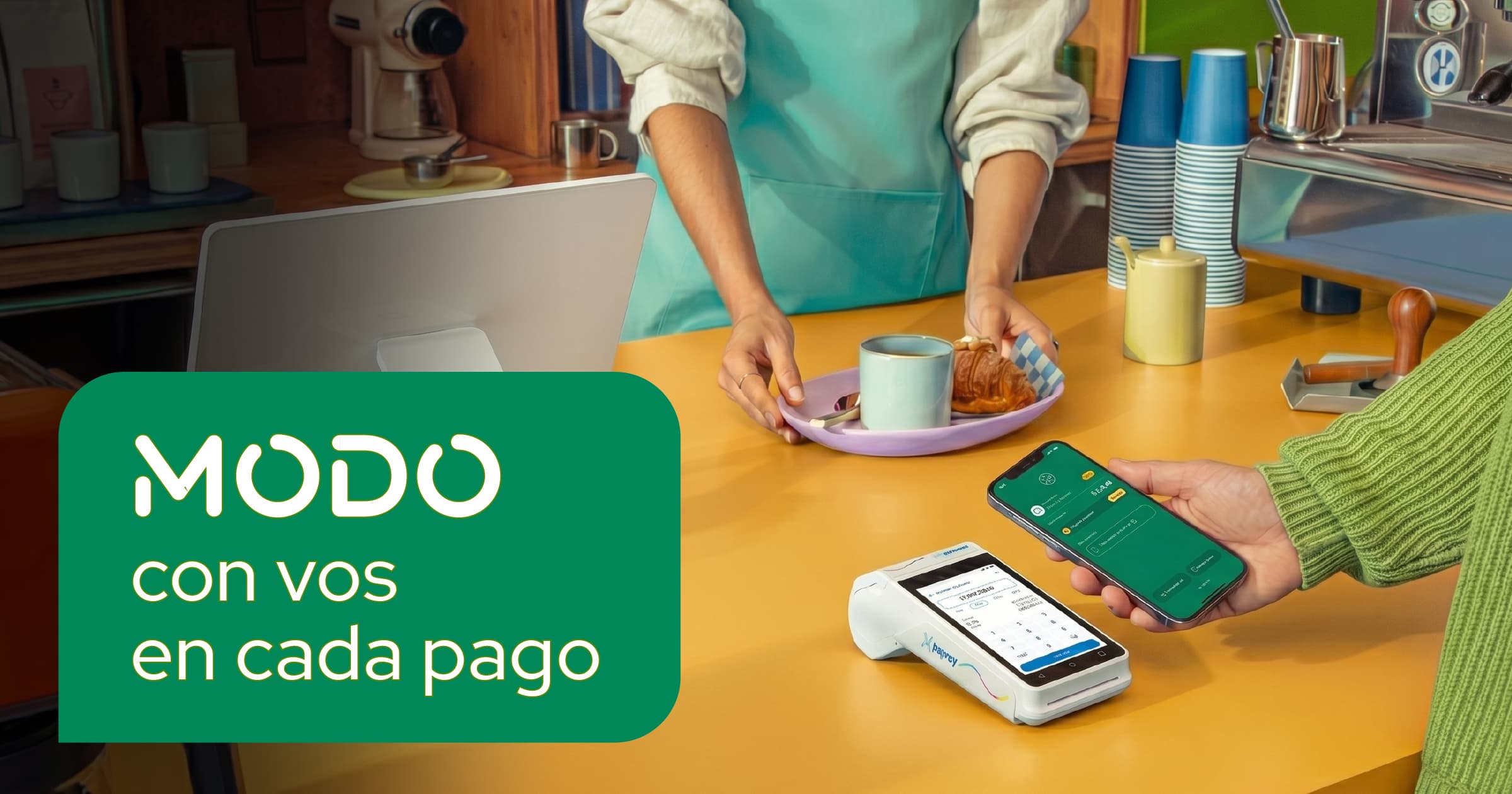 Imagen publicitaria de MODO con el texto "MODO con vos en cada pago". Muestra a un cliente en una cafetería a punto de pagar con la aplicación en su celular frente a una terminal de cobro, mientras recibe su pedido.